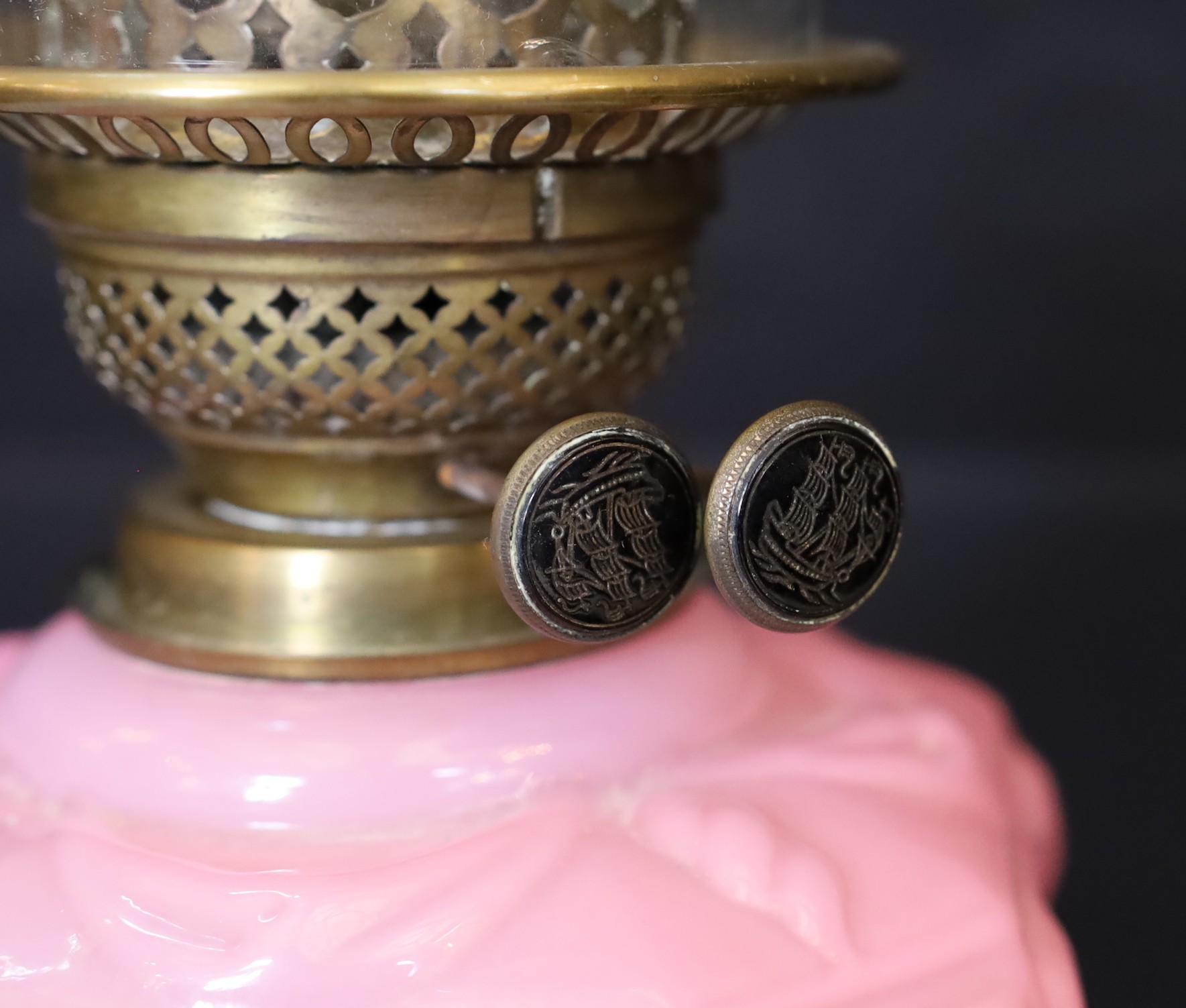 An Edwardian brass Corinthian column oil lamp with opaque pink glass reservoir, etched glass globe and flue, height overall 80cm